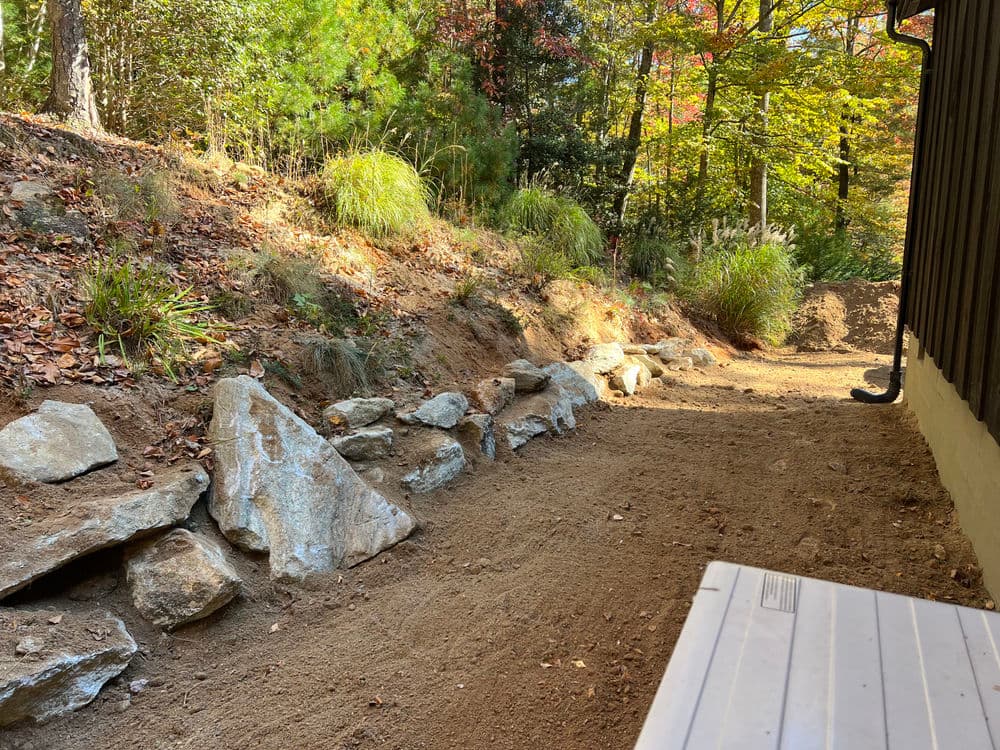 Landscaped path with rocks and greenery, nestled among autumn trees in a wooded area.