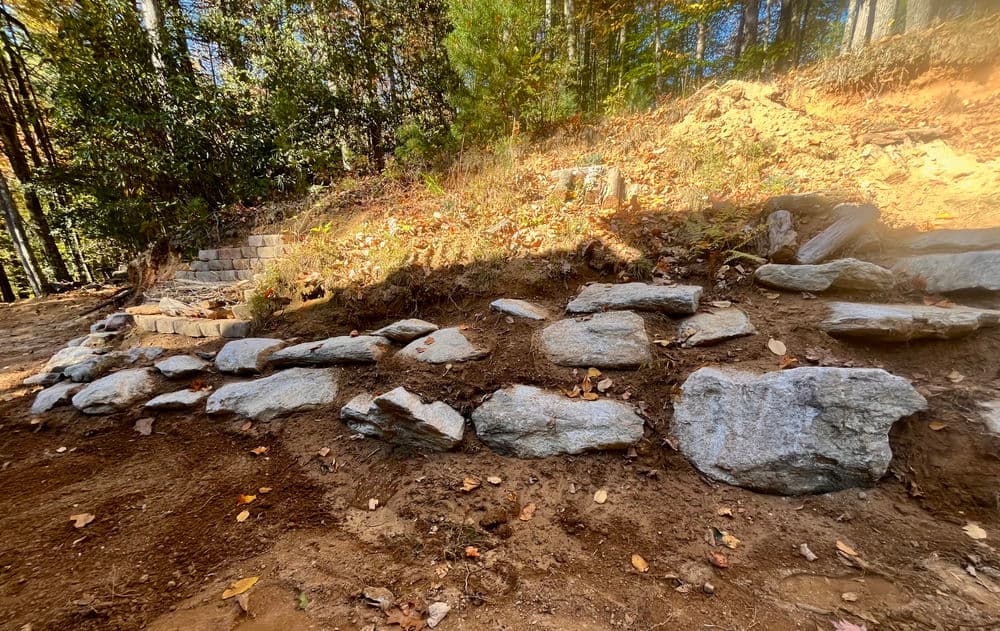 Natural rock landscaping with stones arranged along a hillside in a forested area.