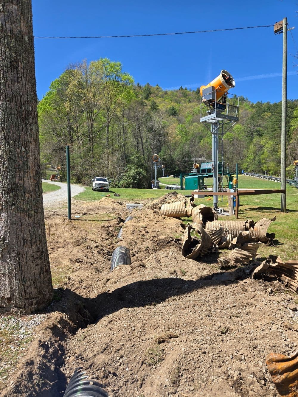 Construction site with excavated ground, drainage pipes, and notification equipment in a rural area.