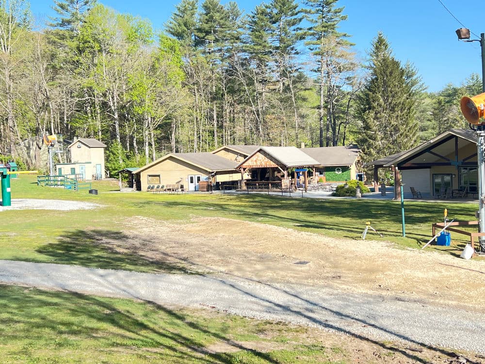 Scenic view of a rustic lodge surrounded by trees and outdoor recreational area.