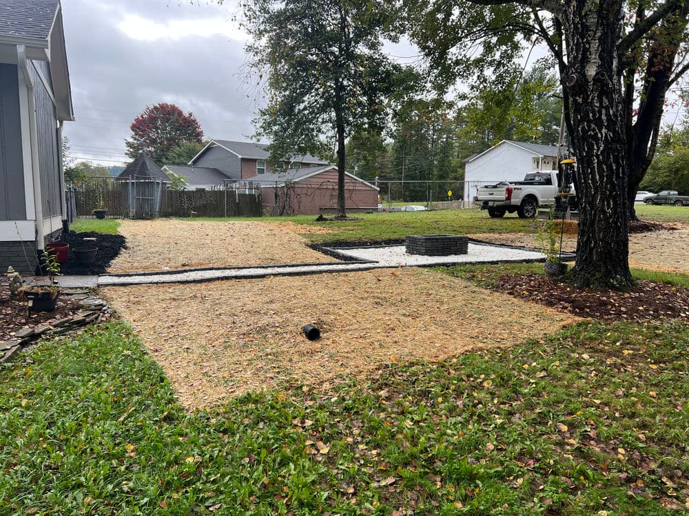 Landscape transformation featuring a gravel patio, fresh grass, and trees in a residential yard.